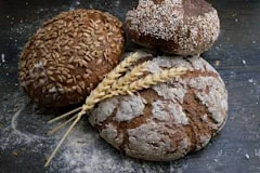 Assorted artisan bread loaves with wheat on a rustic surface