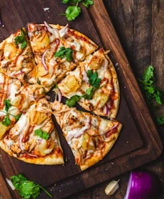 Freshly baked pizza slices with herbs served on a wooden board