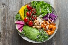 Colorful healthy salad bowl with avocado, chickpeas, greens, and vegetables